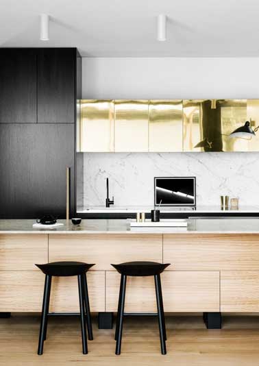 Luxueuse crédence en marbre gris pour cette cuisine design. Assortie au plan de travail, à la façade aspect feuille d'or et aux meubles en bois exotiques