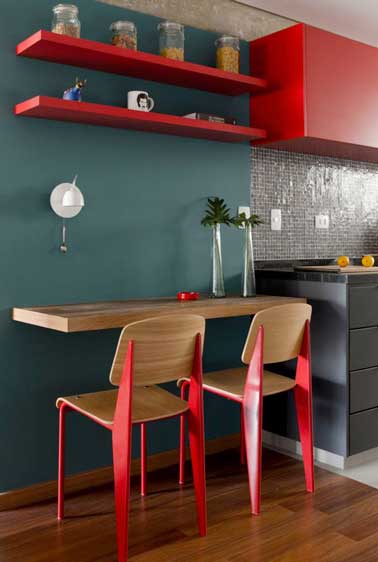 La peinture rouge de la cuisine grise fait le style urbain de cette petite pièce. Le bois choisit sur les chaises, la table et le parquet délimitent l'espace