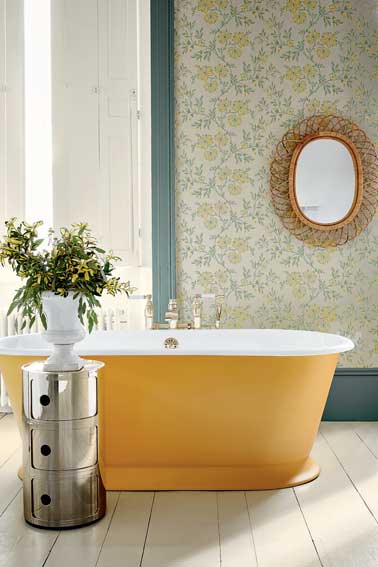 Salle de bain chicissime avec ce papier de peint rétro aux tons pastels vert et jaune. Accordé à la baignoire îlot orange. Stitch papier peint Little Greene