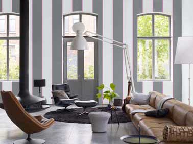 Déco moderne dans le salon couleur peinture gris astrakan et blanc. Halogène blanc et pouf gris clair design. Canapé cuir camel, tapis de sol chocolat chic