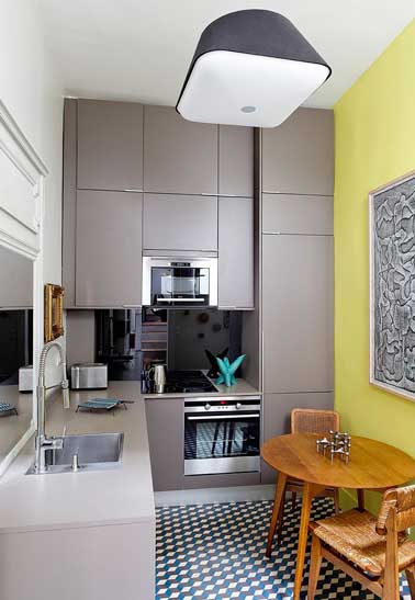Petite cuisine top design avec des meubles de rangements pratiques sur mesure. En déco le sol carreaux de ciment 3d et le miroir de crédence ouvrent l'espace