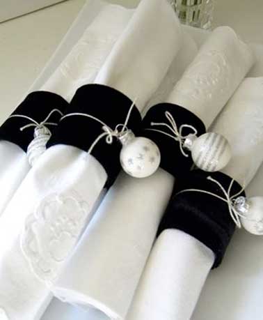 Un beau pliage de serviette à réaliser en déco de table de Noël sophistiquée. Avec des ronds de serviette et boules de Noël en couleurs chic blanc et argent 