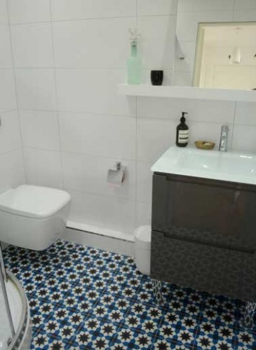 Carreaux de ciment mosaïque bleue pour une salle de bain zen. Murs en carrelage blanc et meuble sous vasque noir laquée se coordonnent parfaitement.