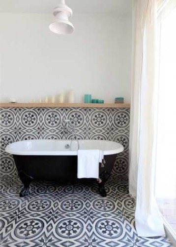 Duo noir et blanc intemporel dans cette salle de bain en carreaux de ciment sur le sol et les murs. Déco construite autour de la baignoire à pieds noir.