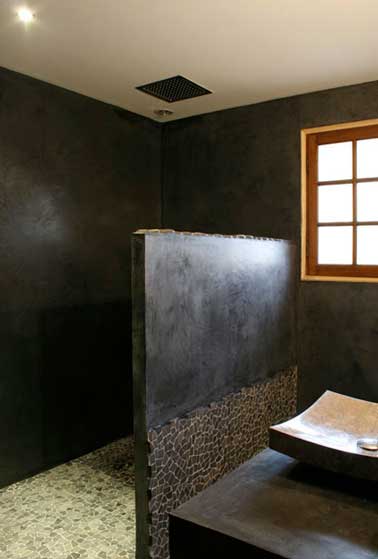 Le béton ciré sur les murs en carrelage de la douche italienne s'associe à des carreaux de mosaïque vert au sol. Le béton fait la déco atypique de la pièce