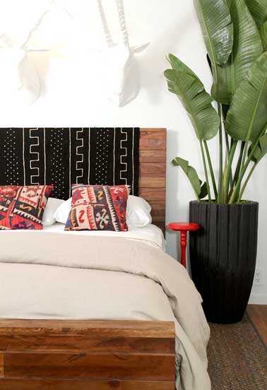 Originale cette tête de lit réalisée en palette de bois avec du tissu artisanal noir et blanc et coussins rouges. Pour une déco exotique dans la chambre. 