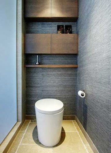 Une cuvette de WC toute ronde pour cette déco zen simple. Carrelage de sol beige et couleurs de murs bleu sombre mettent en valeur les toilettes et les rangements en bois. 