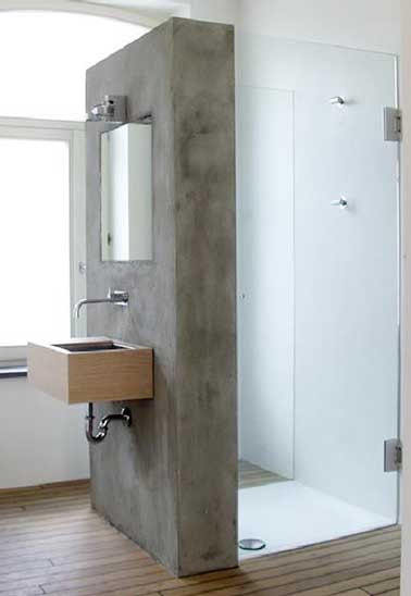 Une cloison de douche faite en béton ciré installe une déco unique dans la salle de bain. Double usage, elle sert aussi de support à la vasque de lavabo bois