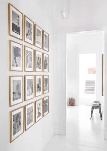 Des cadres photos accrochés sur les murs blancs font la déco. Les photos disposées de façon symétrique dans un style galerie donnent de la couleur à l'entrée