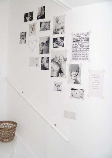 Des photos sont accrochées sans faire de trous contre un mur de l'escalier. A refaire avec du masking tape pour faire rapidement une déco avec vos souvenirs
