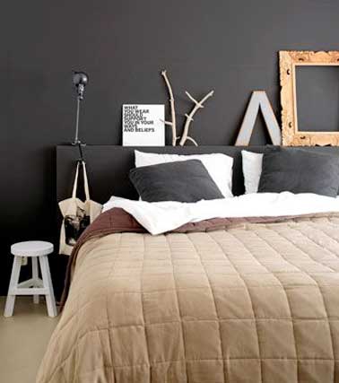 Tête de lit réalisée en coffrage bois et peinte de la même couleur chocolat que les murs. Mise en valeur par le tabouret chevet blanc et le cadre en bois chiné