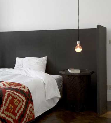 Tête de lit et chevet en aggloméré marine signent le style nordique de la chambre. Mise en valeur par une suspension lumineuse design et une housse de couette effet patchwork