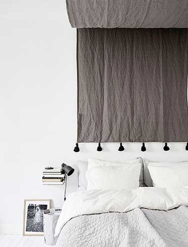 Tête de lit ethnique faite avec le lin taupe du ciel de lit pour réveiller la chambre blanche. Accordée avec les couleurs du panier en tissu, cadre photo et de la lampe à pince 