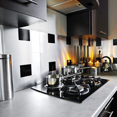 Crédence de cuisine faite avec des carreaux adhésif aluminium finition intox brossé. Ici avec un plan de travail en pierre et des meubles de cuisine design