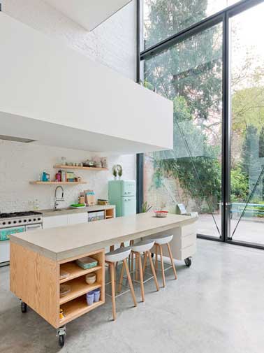 Un mix de déco rétro et design pour la cuisine ouverte sur verrière. Portes coulissantes gain de place, îlot central sur roulette et niches de rangement en font une pièce ultra pratique