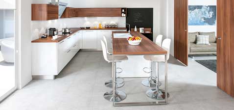 Une grande cuisine ouverte en déco meubles blanc et bois. La cloison fonctionnelle sépare les espaces pour plus de confort. Cuisine Strass 1 en blanc Schmidt