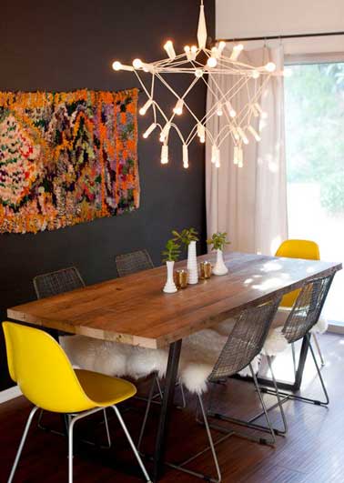 Chaises coques jaune pour animer la déco scandinave de cette pièce aux murs noirs. Une couleur claire et moderne assortie à la suspension lumineuse moderne
