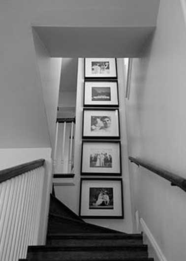 Des cadres photos noirs suspendus dans l'escalier jouent avec la belle hauteur sous plafond. Accrochés sur le mur gris perle ils ajoutent de la profondeur
