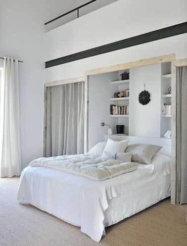 Des niches murales servent à faire un dressing dans la chambre parentale. Déco cosy avec les rideaux en velours taupe et le linge de lit cocooning