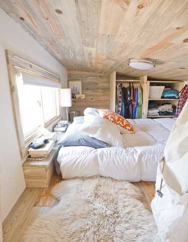 Un mini dressing ouvert dans la petite chambre parentale d’un tiny house. Fait avec le bois de construction il a une partie étagères et une penderie