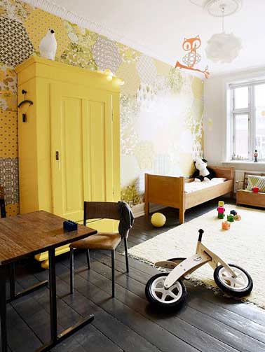 Repeint en couleur de peinture jaune, l'armoire de la chambre enfant apporte une note rigolote à la déco. Associée avec du papier peint à motifs coordonnés