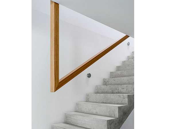 Ultra moderne la cage d’escalier aux murs blancs avec sa rampe en bois design et son esacalier en béton. Le bois blond apporte de la chaleur à cette déco froide 