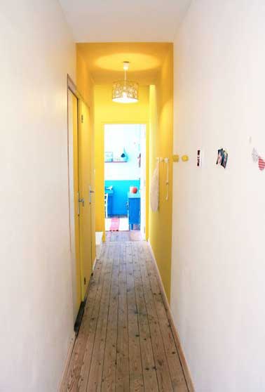 Une partie du couloir est peint avec une couleur jaune pour amener relief et lumière dans cet espace étroit. Pour plus d'effet un luminaire éclaire le jaune 