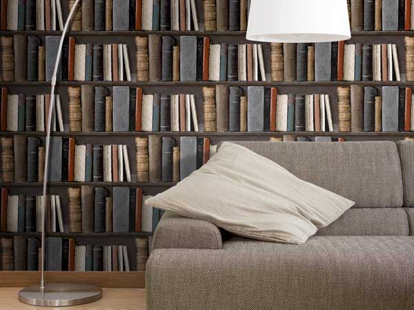 Un papier peint salon vinyle intissé trompe l'oeil bibliothèque décore la pièce. Luminaire design blanc et canapé en tissu taupe complètent cette déco cosy