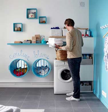 Des paniers de rangement pour le linge sont encastrés dans la cloison attenante de la salle de bain. Et un mur profite d’étagère filante et de boîtes fermées