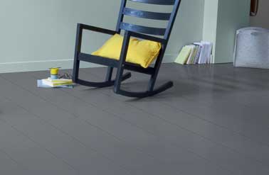 Déco industrielle avec cette peinture parquet gris ardoise sur le sol du salon. Avec des murs vert d’eau, une chaise bascule design noir et des notes jaune