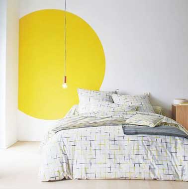 Un rond de peinture jaune punchy anime la déco de cette chambre blanche épurée. Dessiner une forme graphique est une idée à reprendre pour réveiller une pièce monochrome
