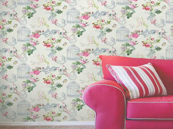 Déco de salon vintage avec un papier peint intissé motifs fleurs roses. Une note rétro et chaleureuse en accord avec le grand canapé en velours framboise