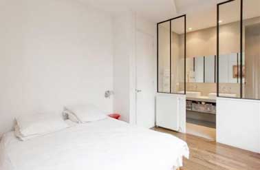 Ambiance loft pour la suite parentale avec une cloison verrière style atelier. Un beau jeu de lumière douce dans la chambre et tamisée dans la salle de bain