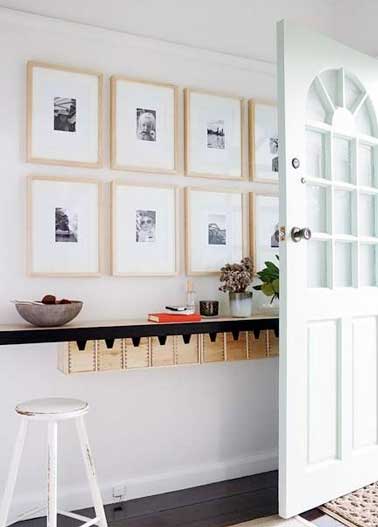 Accrochés contre le mur sur deux niveaux les cadres photos en bois clair habillent l'entrée avec élégance. Une déco simple et graphique pour les petits espaces