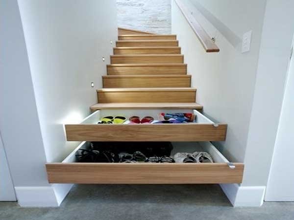 Des tiroirs de rangement sont aménagés dans les marches de l’escalier en bois. Une astuce gain de place pour les petits espaces. Ici avec des murs peints en blanc