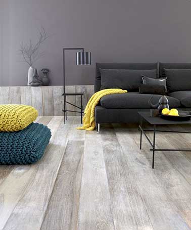 Plaid et coussins jaunes dynamisent le canapé noir et les tons sombres du salon gris. Placées en touche de couleur ils réveillent le camaïeux gris de la pièce