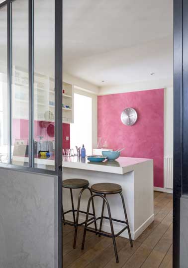 Peinture à effet nacré rouge dans cuisine ouverte mixée avec une couleur ardoise sur le soubassement de la porte verrière. Look industriel avec tabouret de bar en bois et détail inox. 