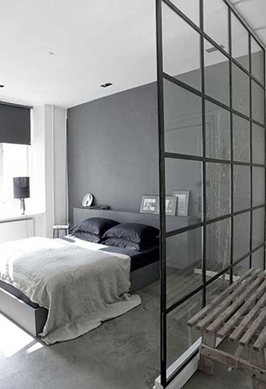 Une verrière intérieure pour créer un coin dressing dans une chambre parentale. Sa structure quadrillée noir se marie avec les oreillers, le rideau et la lampe de chevet design