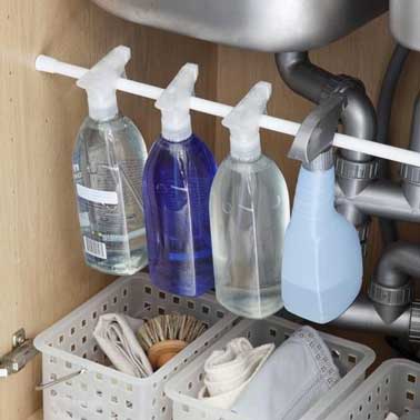 Astuce rangement cuisine pour produits entretien sous l'évier Pour ranger les produits d'entretien dans une cuisine, le meuble sous évier s'organise avec des paniers en plastique et une barre pour suspendre spray et vaporisateurs, de sorte à gagner de la place pour ranger tous les accessoires.