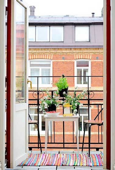 Adopter un accessoire de couleur sur son balcon est une bonne astuce pour moduler sa déco sans refaire tout l’agencement d’extérieur. Ici un tapis de sol multicolore est placé sur la terrasse