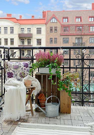 Sur le balcon, un coin jardin suspendu est aménagé sur des vieilles caisses récup. Une chaise pliante en bois et un arrosoir en acier galvanisé signent une déco romantique