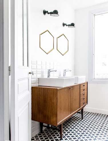Salle de bain transformée avec un sol en carreaux de ciment à motifs géométrique blancs et noirs. Associé avec un carrelage métro blancs sur le mur et un bahut scandinave relookée en lavabo