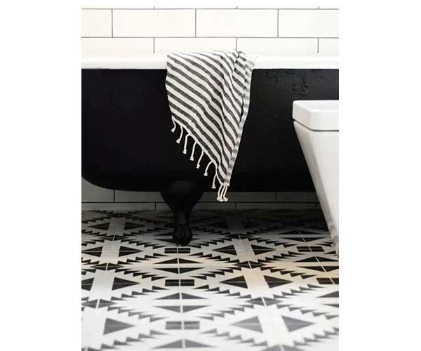 Déco graphique dans cette salle de bain avec un sol en carreaux de ciment noirs et blancs. Baignoire îlot noir et carrelage métro blanc complètent l'ensemble