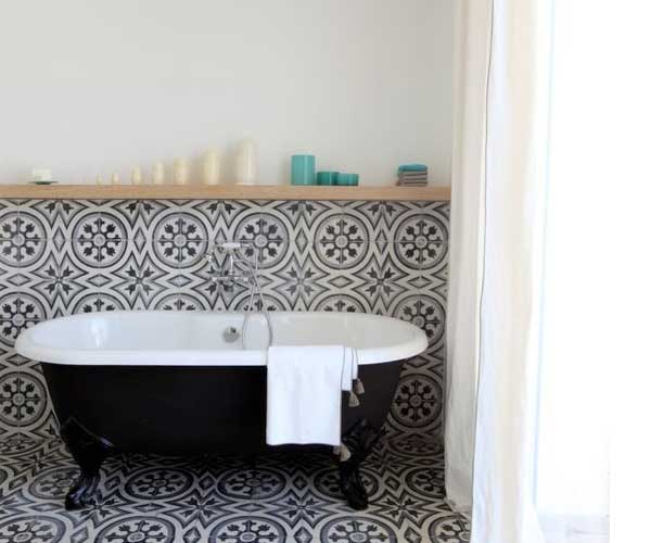Une salle de bain qui mixe les genres avec une baignoire pied et un carrelage de sel en carreaux de ciment vintage. Et une étagère bois contemporaine. 
