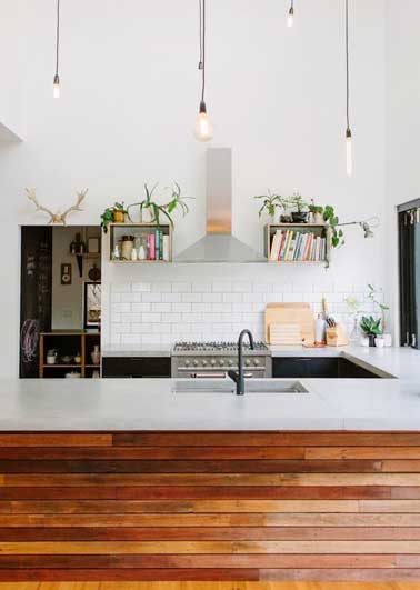 Carrelage métro et murs blancs donne une note industrielle à cette déco de cuisine. Structurée avec plan de travail en pierre blanche et bloc en bois exotique et éclairée par suspension loft