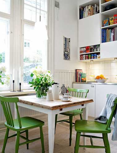 Table avec plateau bois pliable pour faire un coin repas gain de place. Assortie avec trois chaises en bois vertes pour colorer meuble de cuisine et murs blancs.