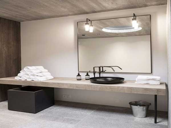 Une salle de bain zen dans une déco épurée à base de matériaux brutes sur le sol en dalle de béton et le plan vasque réalisé sur mesure en bois brut