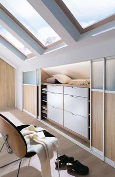 Chambre sous pente avec dressing sur mesure à portes coulissantes en mélaminé et verre silver. Colonnes sur pieds, étagères coulissantes avec casier bambou et coffre rentrant. Mobalpa