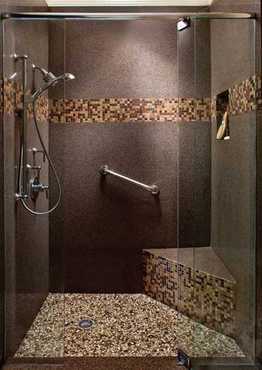 Douche à l’italienne avec frise en mosaïque et receveur de douche encastré dans un sol en granit. Rampe d’appui de douche et banc sont l'atout confort de la douche