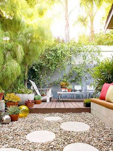 Terrasse aménagée en deux parties. Coin détente pour la terrasse surélevée en teck agrémentée de chaises longues et espace jardin zen avec des pas japonais sur un parterre de galet.